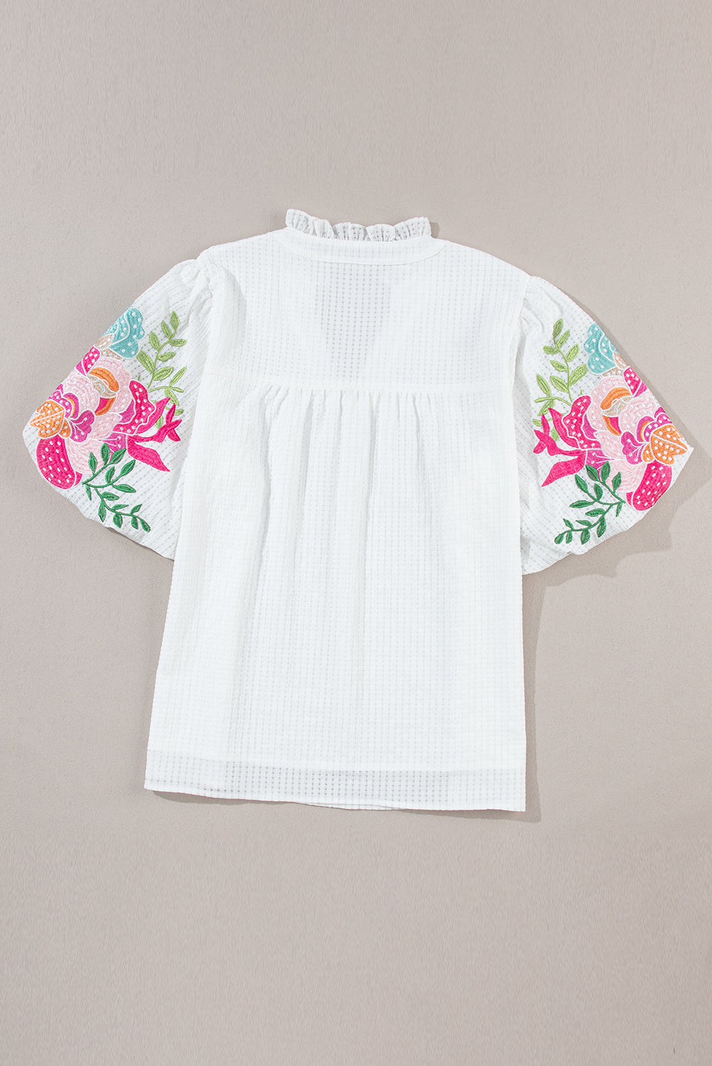 Blouse blanche à col cranté et manches bouffantes brodées de fleurs