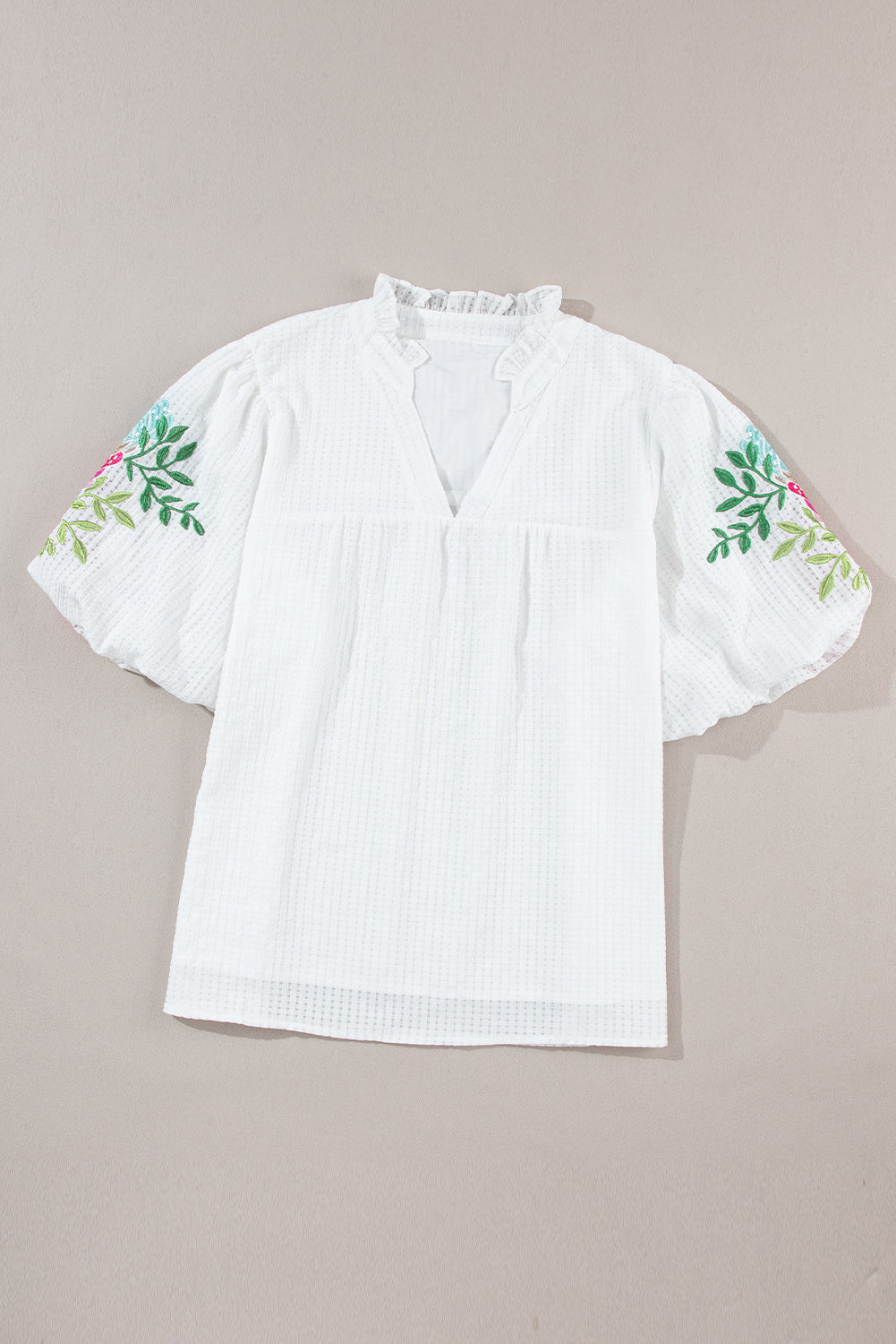 Blouse blanche à col cranté et manches bouffantes brodées de fleurs