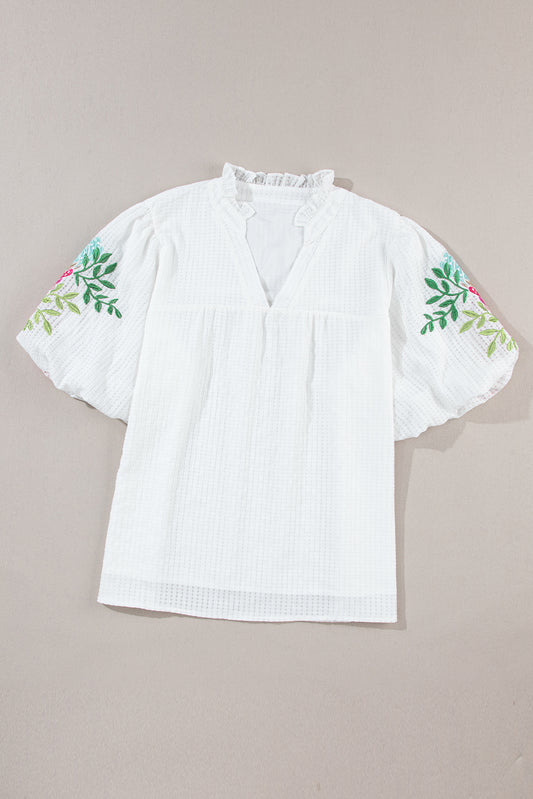 Blouse blanche à col cranté et manches bouffantes brodées de fleurs