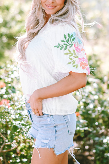 Blouse blanche à col cranté et manches bouffantes brodées de fleurs