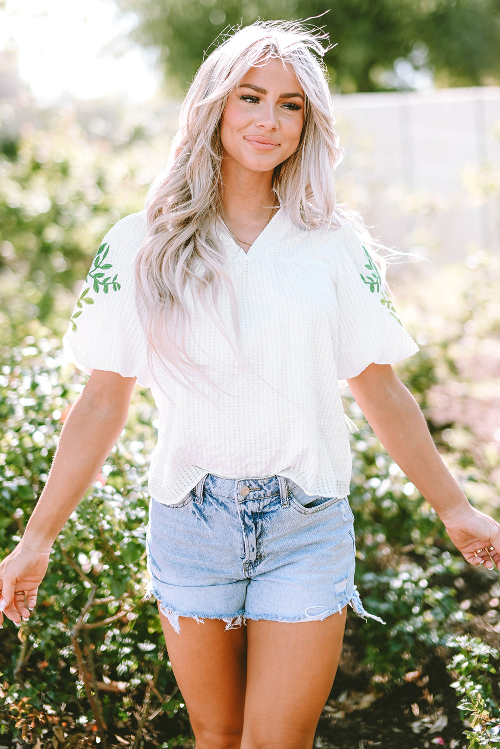 Blouse blanche à col cranté et manches bouffantes brodées de fleurs