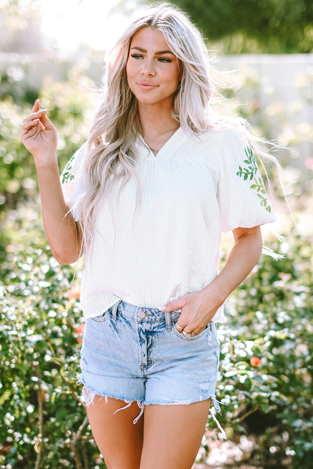 Blouse blanche à col cranté et manches bouffantes brodées de fleurs