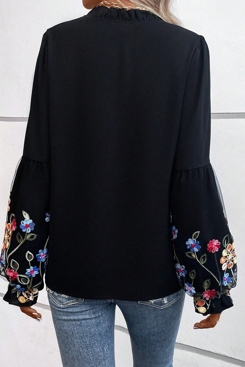 Blouse noire à col fendu et manches volantées à patchs floraux